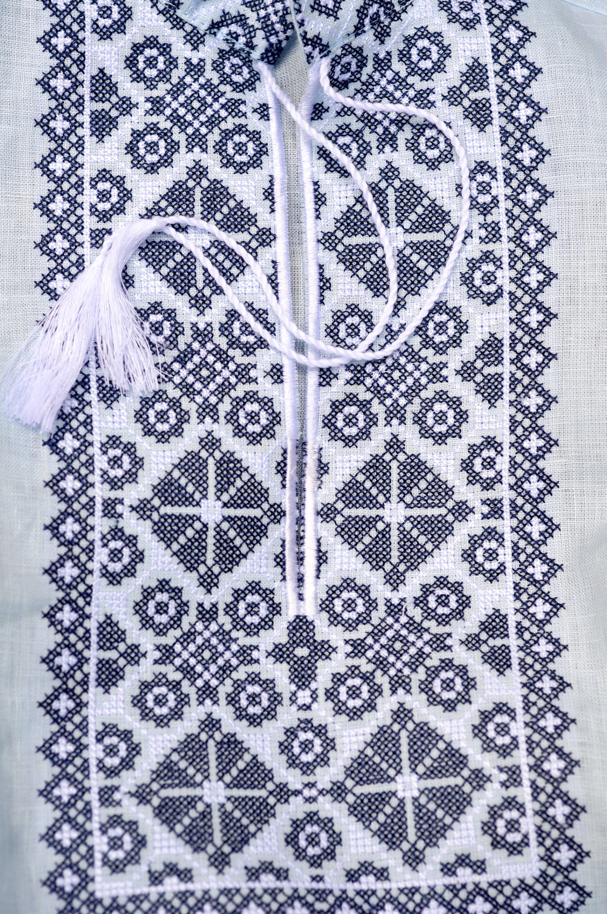 Close-up of dark geometric embroidery on a light blue boys’ emboidered shirt