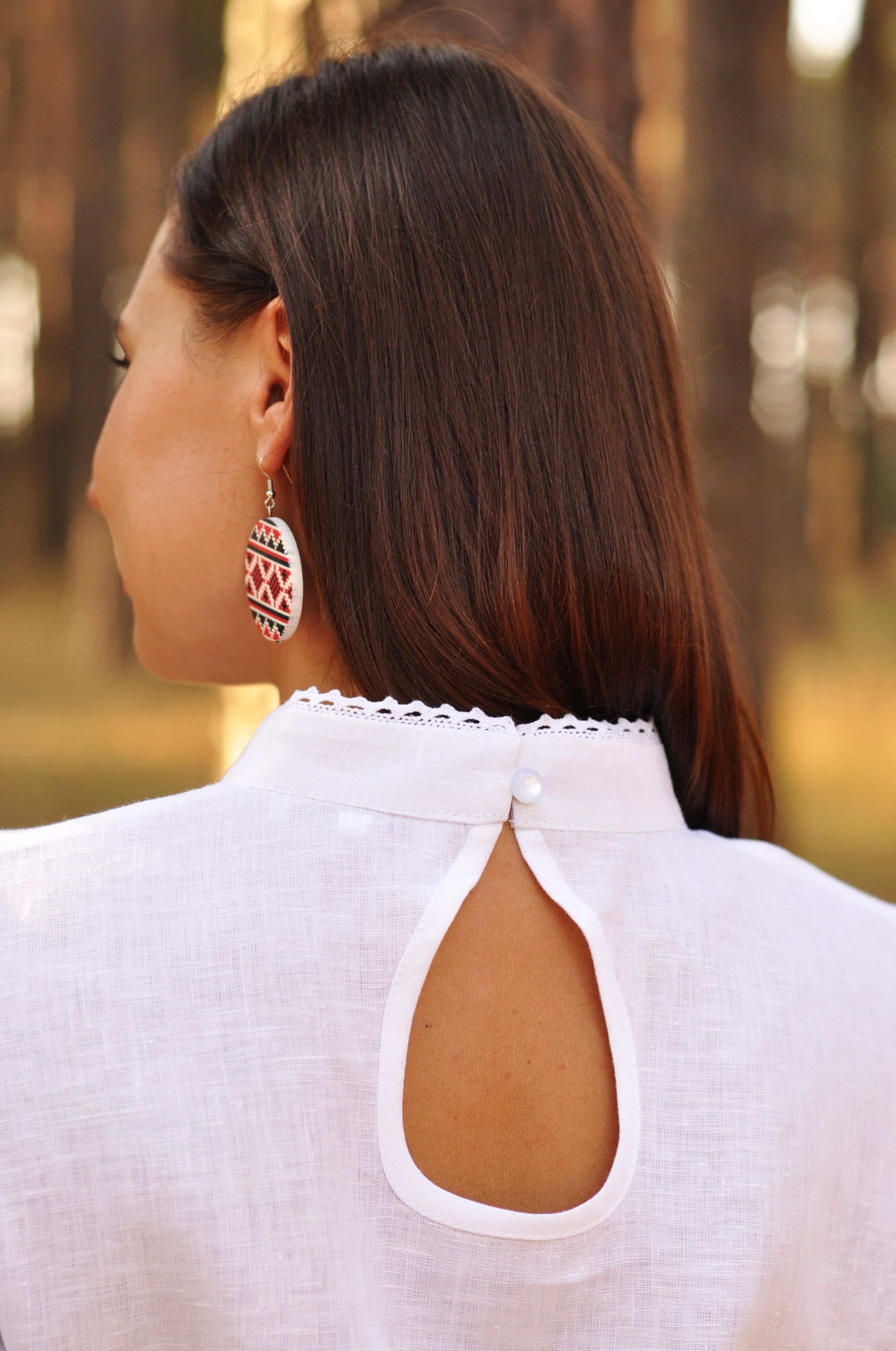 Woman wearing a white blouse with cut-out design in an outdoor setting