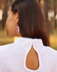 Woman wearing a white blouse with cut-out design in an outdoor setting